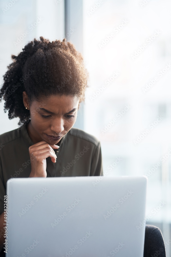 Head down, time to work hard. Shot of a young businesswoman using a laptop in a modern office.