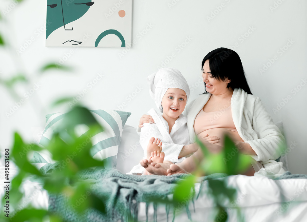 Little girl with her pregnant mother at home in morning