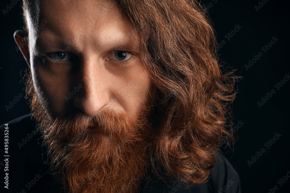 Portrait of young bearded man on black background, closeup