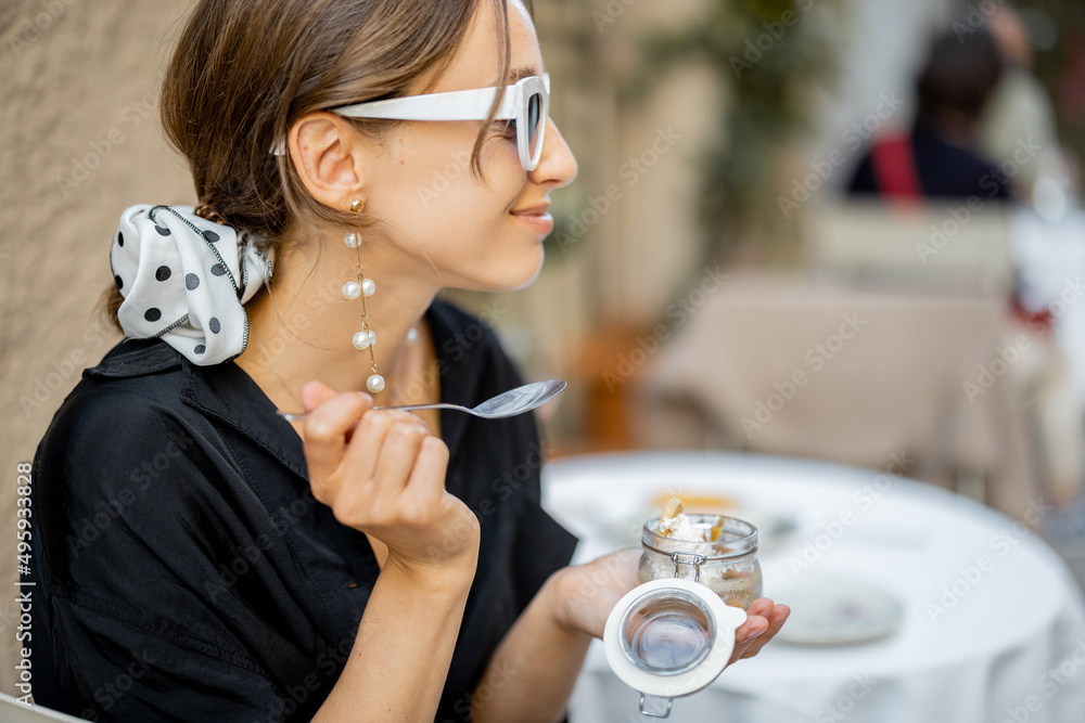 在户外餐厅吃提拉米苏甜点的女人。意大利美食的概念