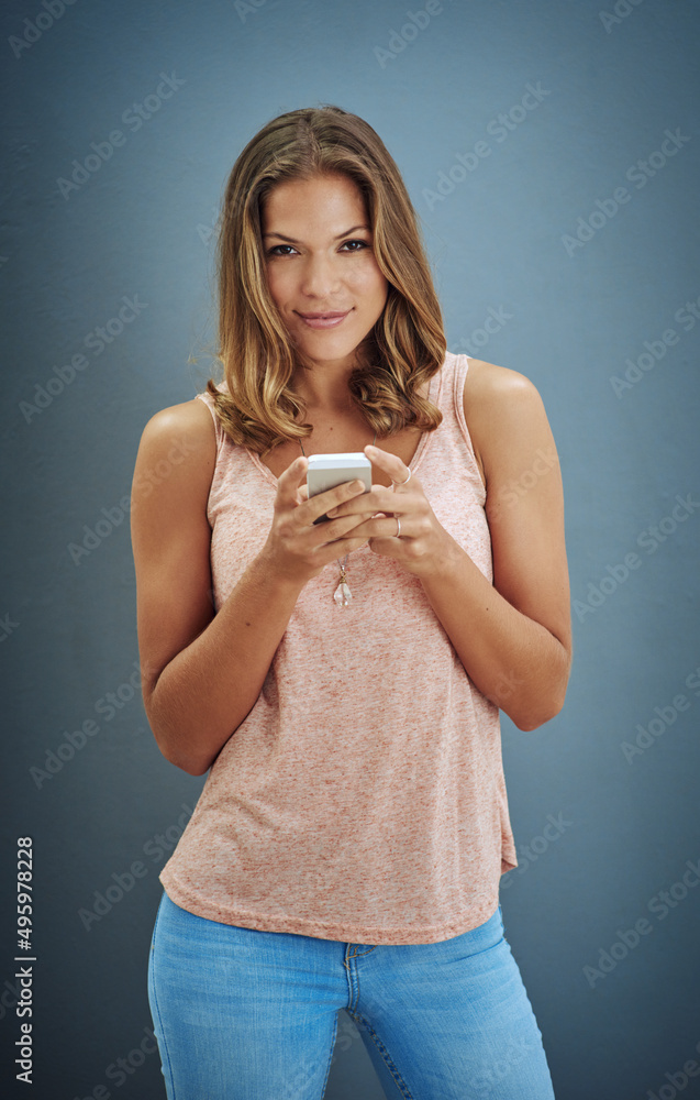 Getting acquainted with my new phone. Studio portrait of a young woman using her cellphone against a