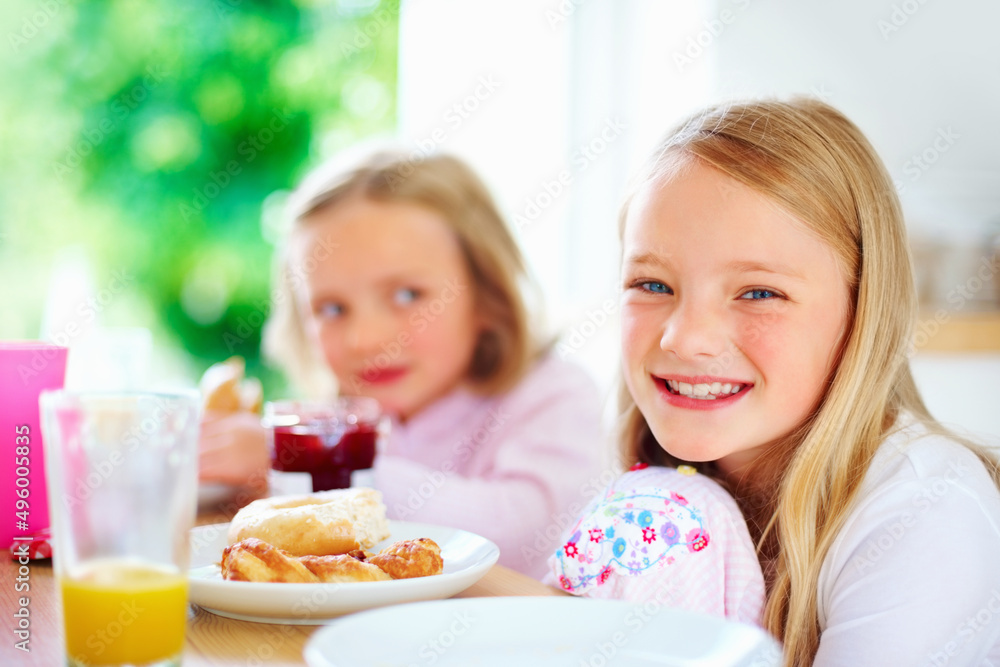 Smiling little girl with her sister having breakfast. Portrait of a smiling little girl with her sis