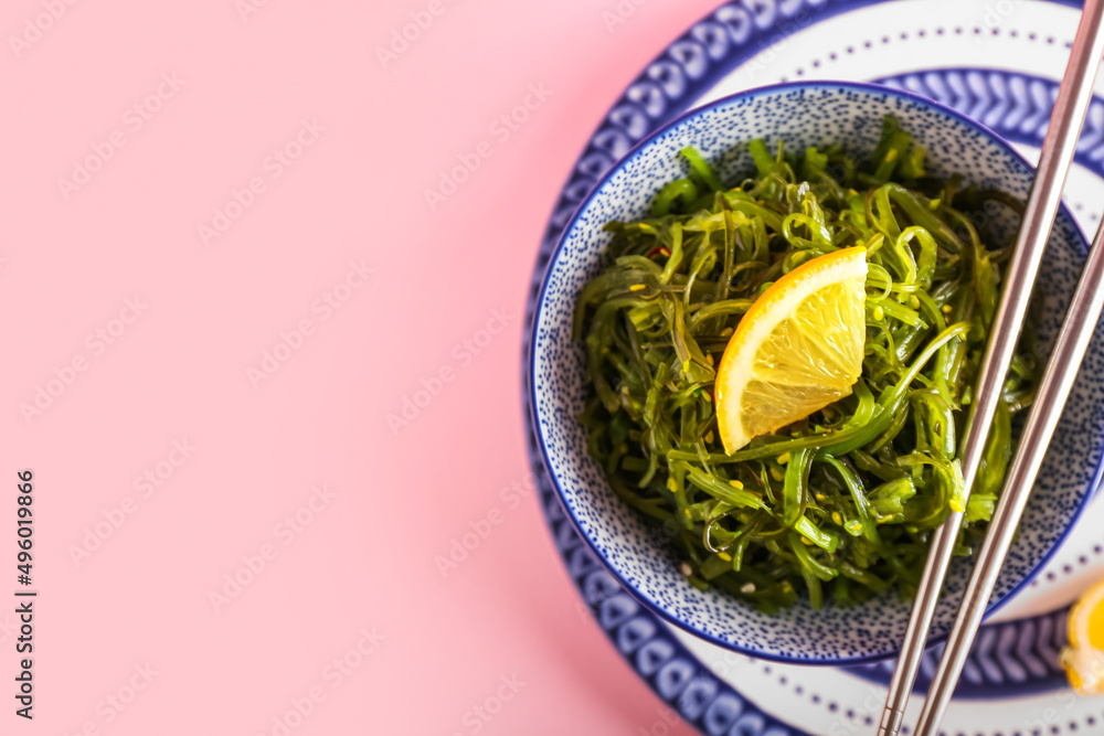 Bowl with healthy seaweed salad on pink background