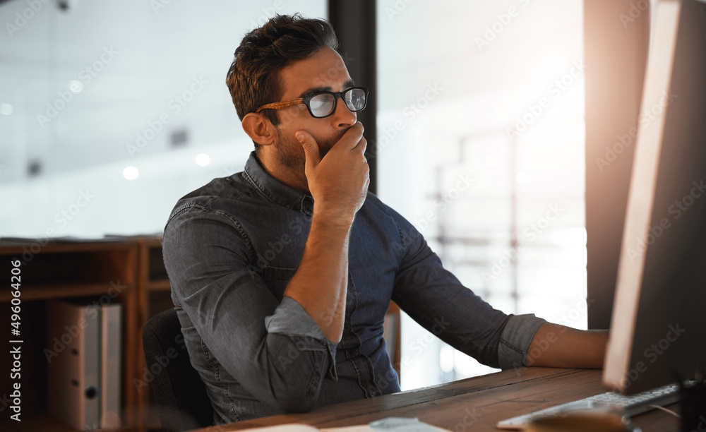 My brain needs a break. Shot of a young businessman yawning while working late on a computer in an o