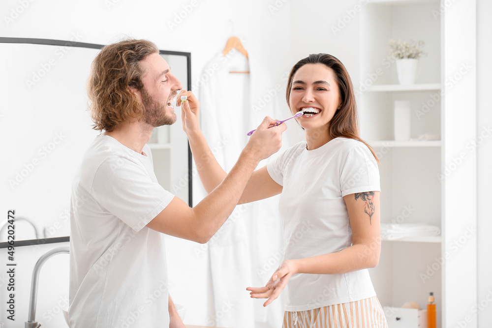 Funny young couple brushing teeth in bathroom