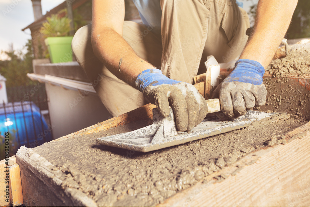 Close-up of a man with trowel make concrete staircase at home