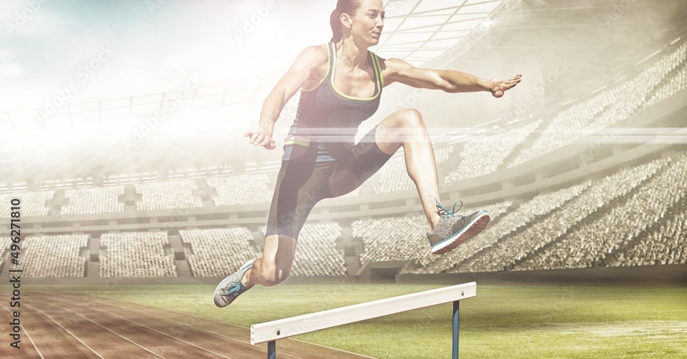 Composite image of caucasian female athlete jumping over hurdles against sports stadium