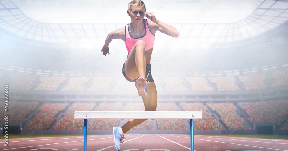 Composite image of caucasian female athlete jumping over hurdles against sports stadium