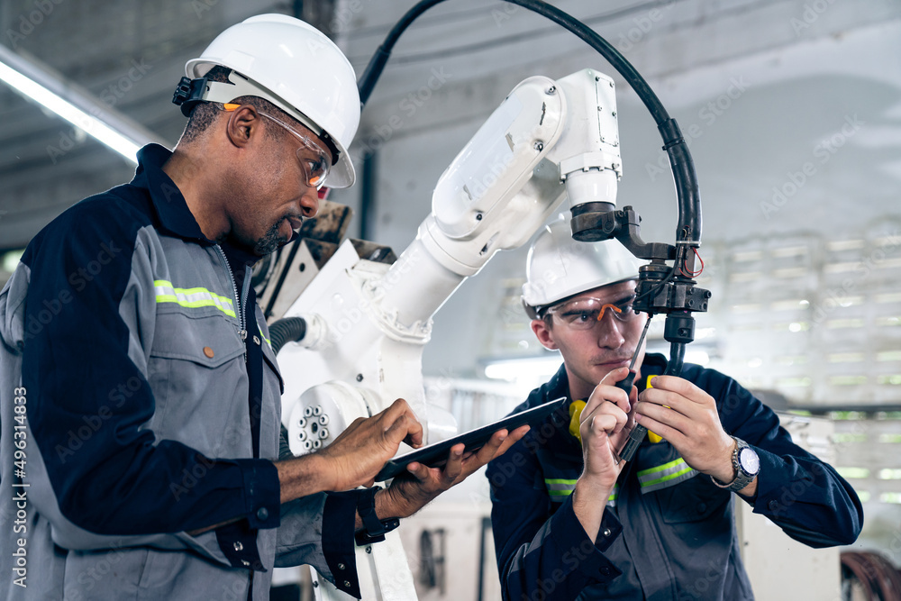 Factory workers working with adept robotic arm in a workshop . Industry robot programming software f