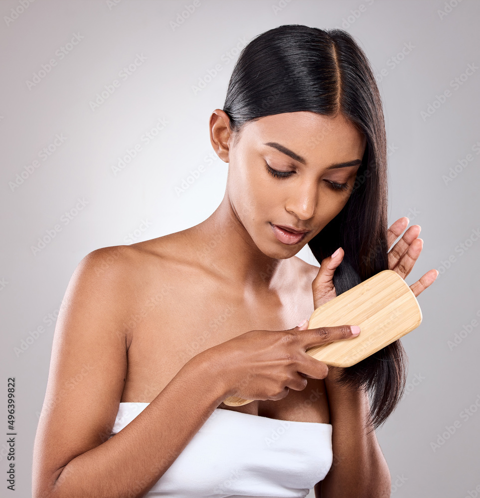 Only through difficulty can you rest. Shot of an attractive young woman brushing her hair against a 