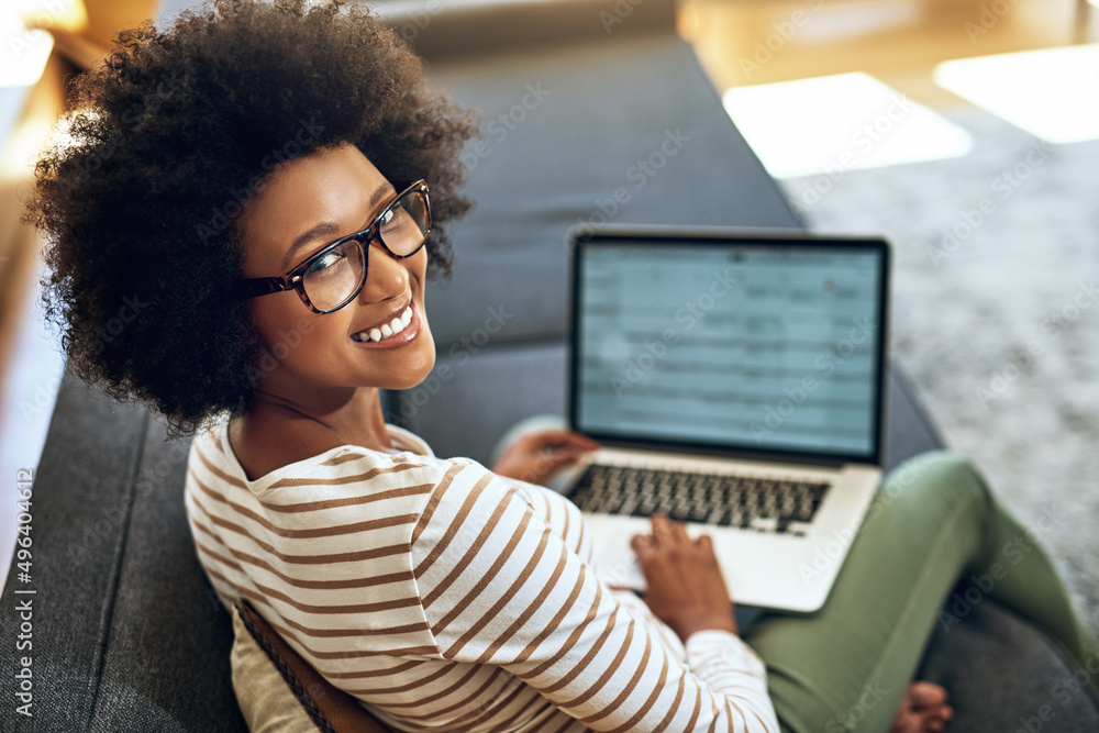 No better way to work than to work from home. Portrait of a cheerful young woman working on her lapt