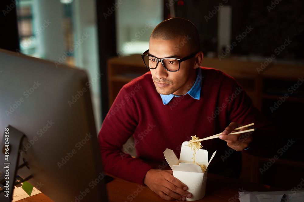 外卖是加班的关键。一个英俊的年轻人在工作时吃中餐的镜头