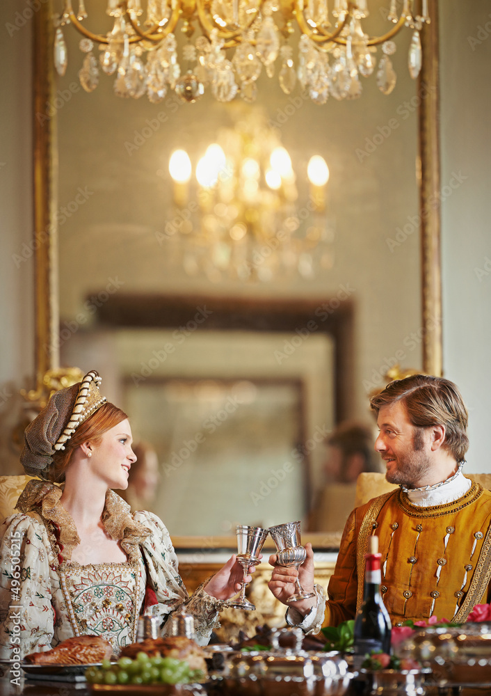 Its been a grand harvest in the kingdom. Shot of a noble couple toasting while eating together in th