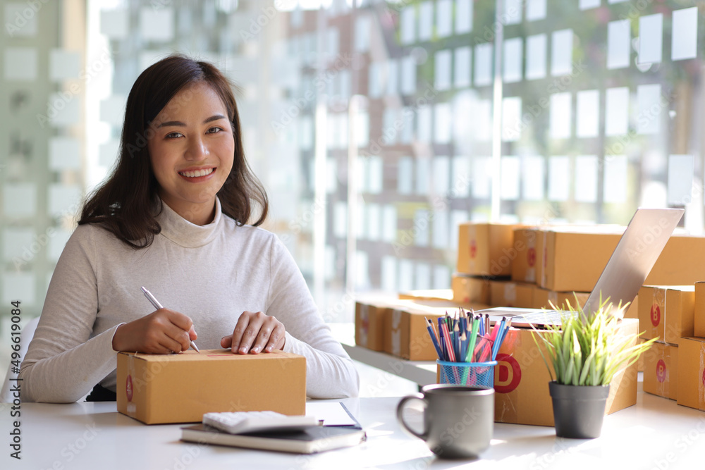 Shipping shopping online, start up small business owner writing address on cardboard box at workplac