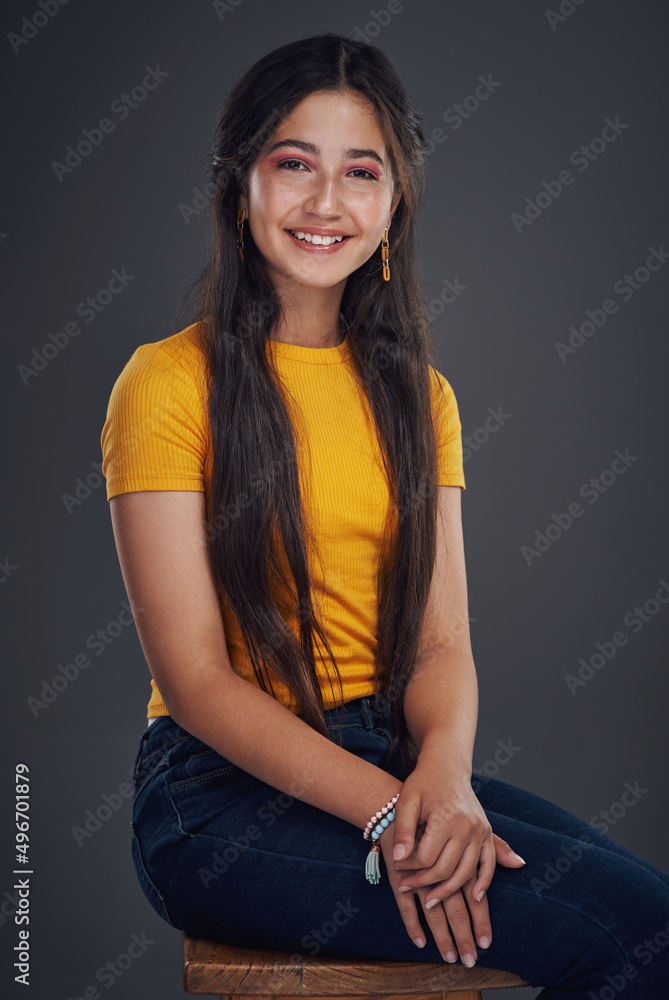 When all else fails, smile. Cropped portrait of an attractive teenage girl sitting alone against a d