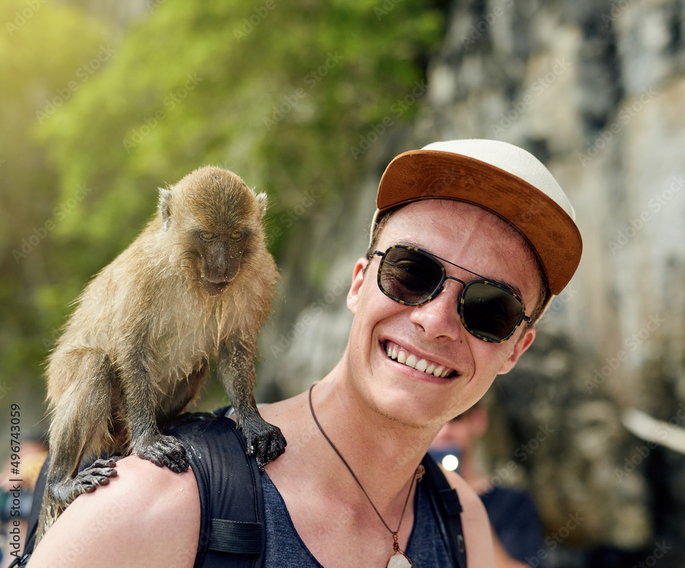 Just monkeying around. Portrait of a young man with a monkey sitting on his shoulder outside.