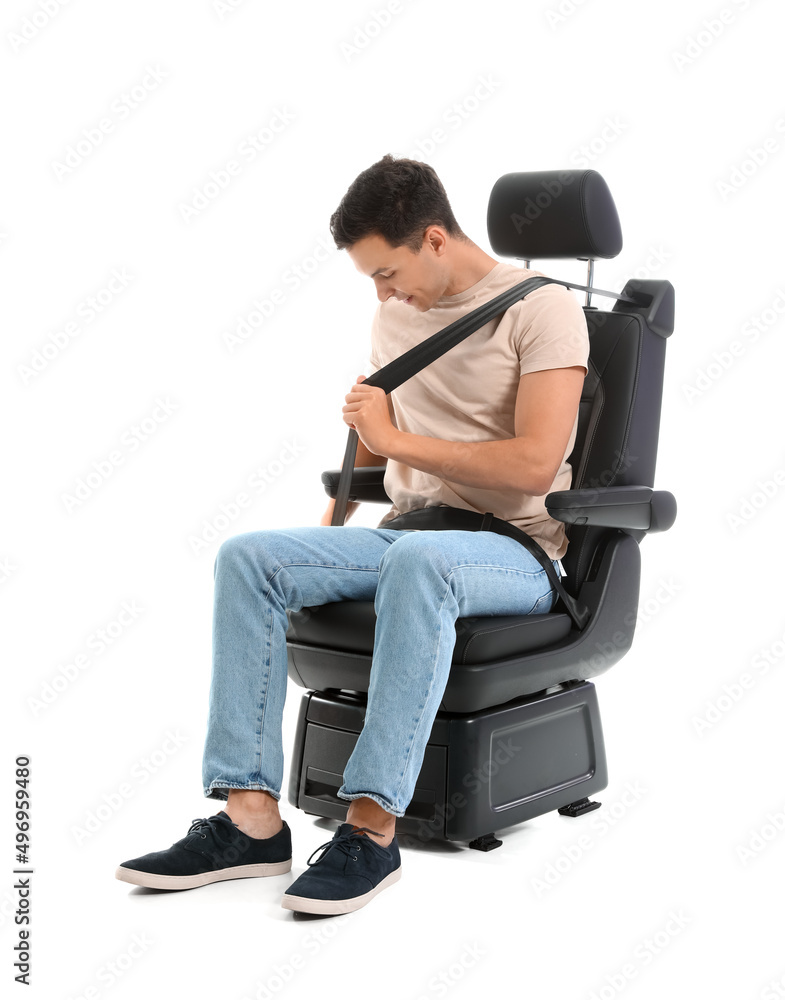 Young man fastening in car seat on white background