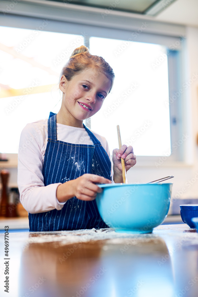 我正在做一些超级美味的食物。一个小女孩在家厨房里烤面包的画像。