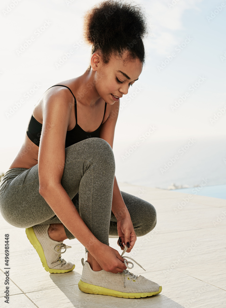 锻炼身体。一个运动型年轻女子在外面系鞋带的镜头。