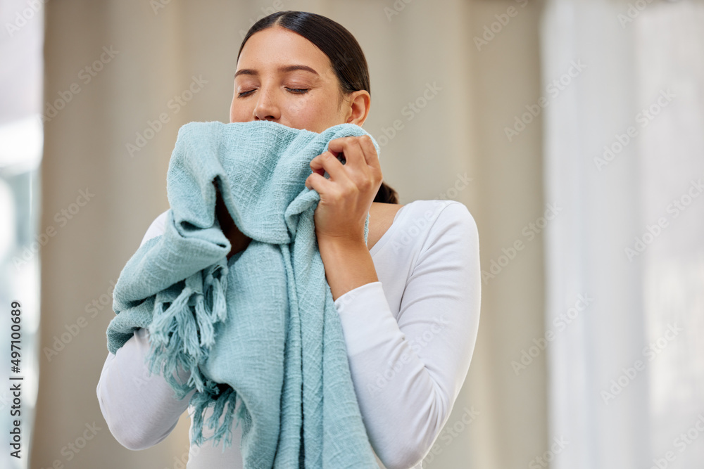 This smell should be bottled. Shot of a young woman smelling freshly cleaned laundry.