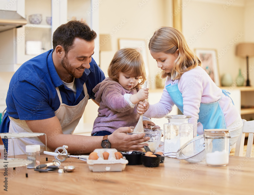 The kitchen is the heart of the home. Shot of a young father baking together while a little girl sti