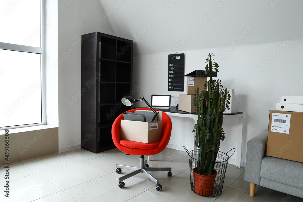 Cardboard boxes with belongings and furniture in interior of office on moving day