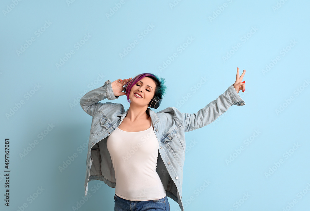 Beautiful woman with unusual hair listening to music on blue background