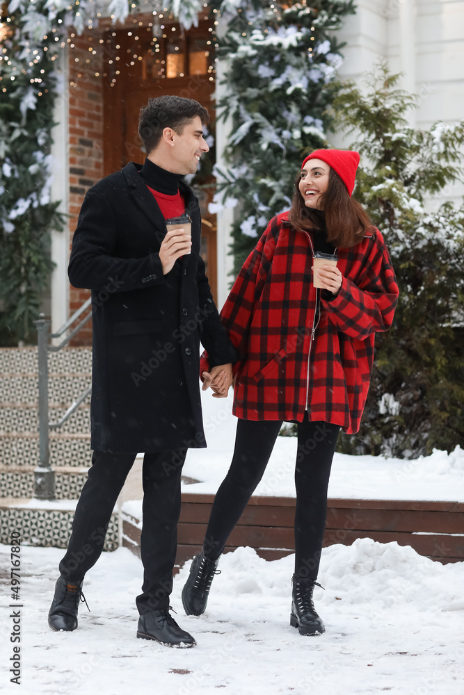 Loving couple with cups of coffee on snowy winter day