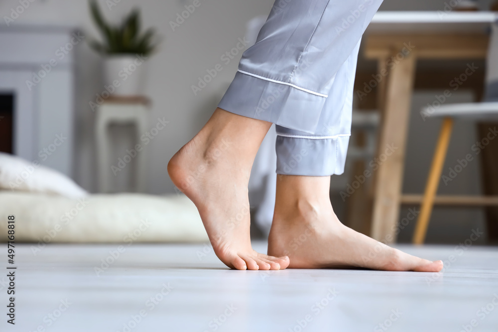 Barefoot woman in pajamas at home, closeup