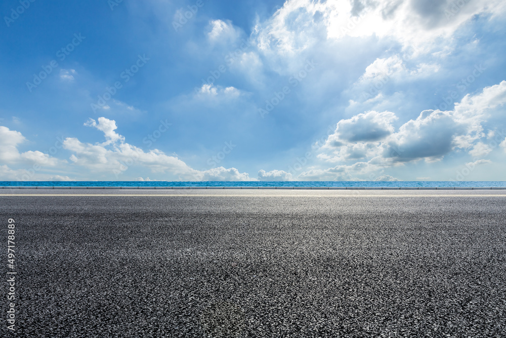 Empty asphalt road near the lake under blue sky