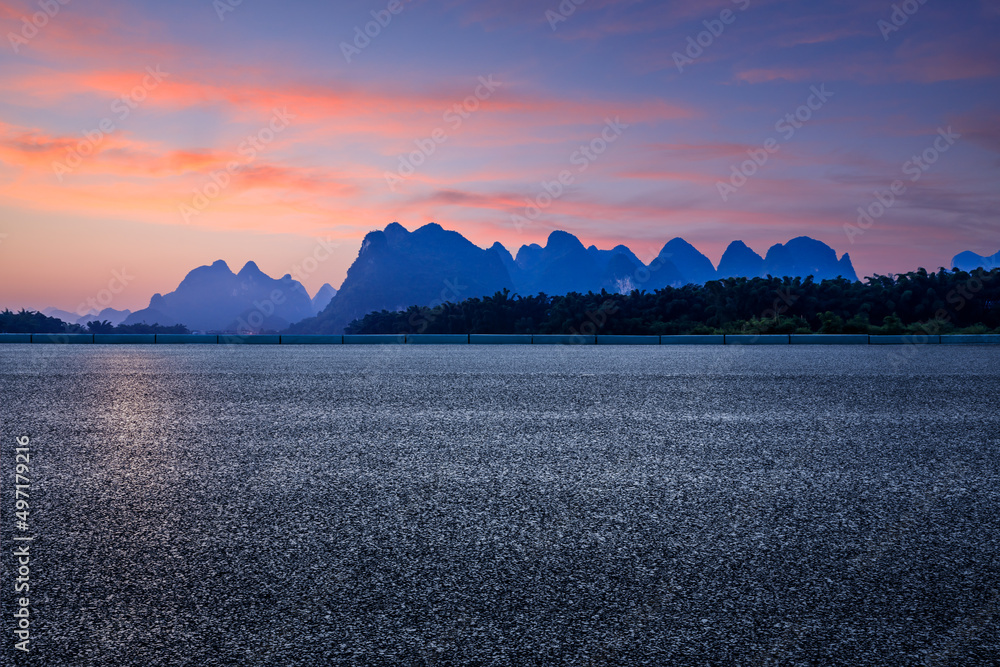 日出时天空乌云密布的柏油路和山