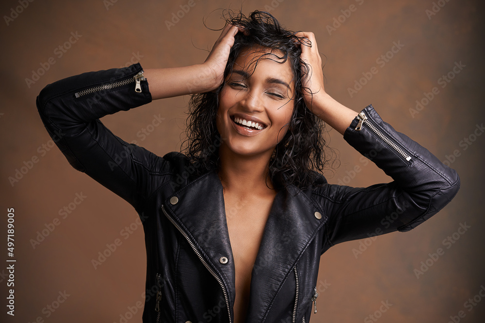 Looking stylish in leather. Studio shot of an attractive young woman in a leather jacket against a b