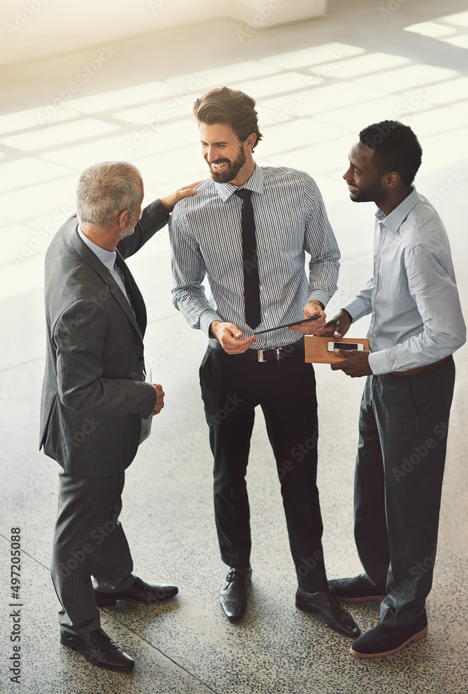 Meeting on the move. High angle shot of businesspeople standing in a office lobby.