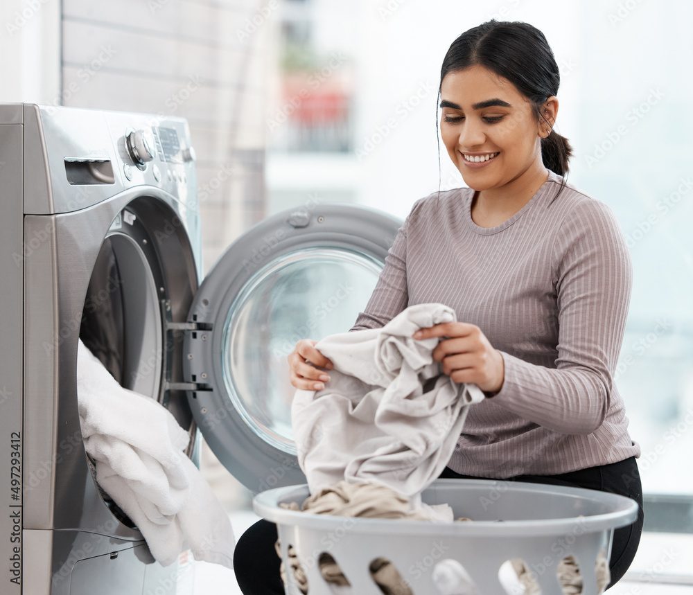 No stains are safe. Shot of a beautiful young woman doing the laundry at home.