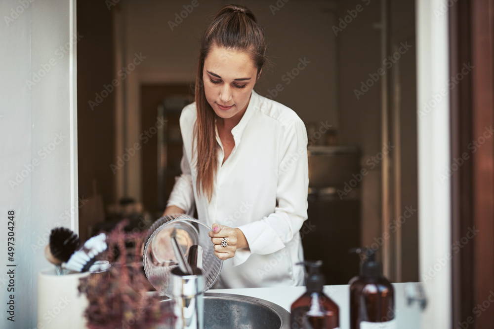 微笑的年轻女子在厨房里洗花瓶