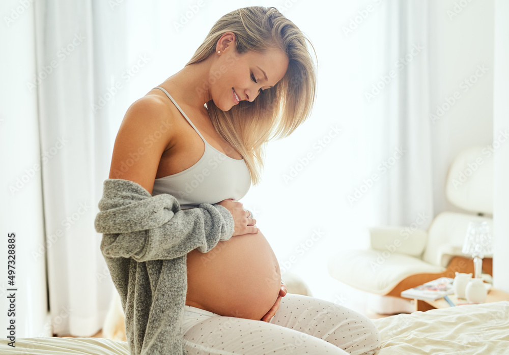 I cant wait to hold you in my arms. Shot of a pregnant woman touching her belly while sitting on her