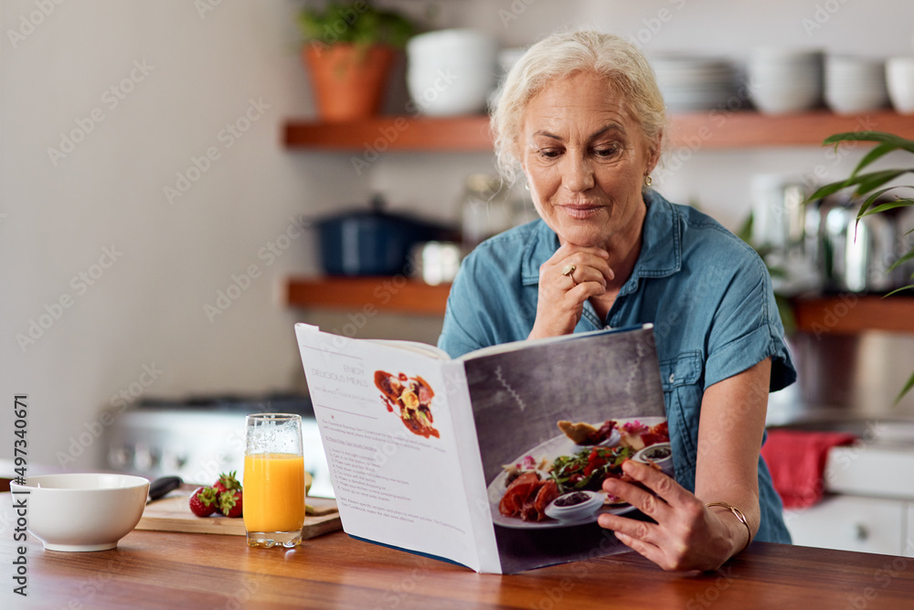 The healthy way is the smart way. Shot of a mature woman reading a book while preparing breakfast at