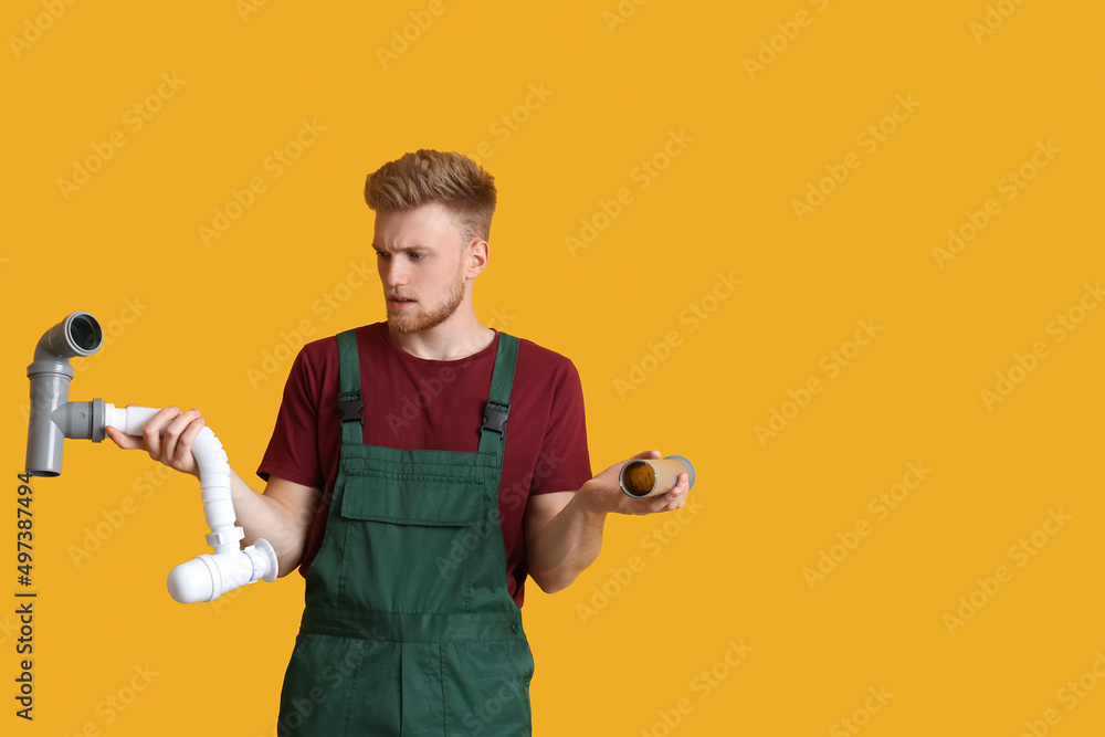 Confused young plumber on color background