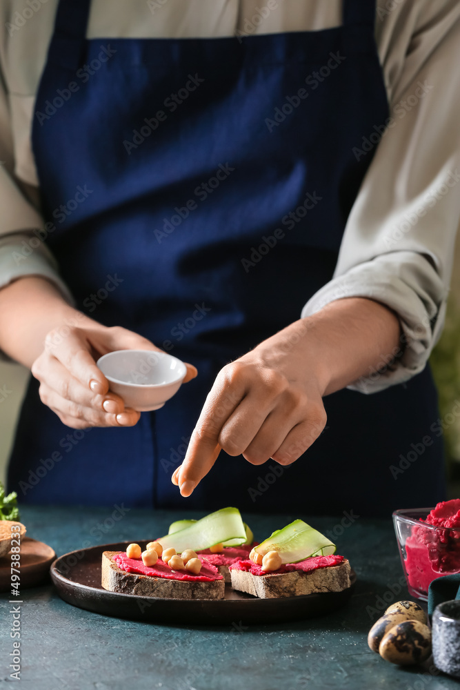 一位女士在餐桌上用健康的鹰嘴豆泥做美味的三明治