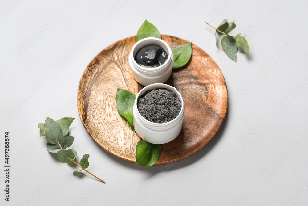 Composition with jars of activated carbon facial mask, powder and eucalyptus branches on white backg