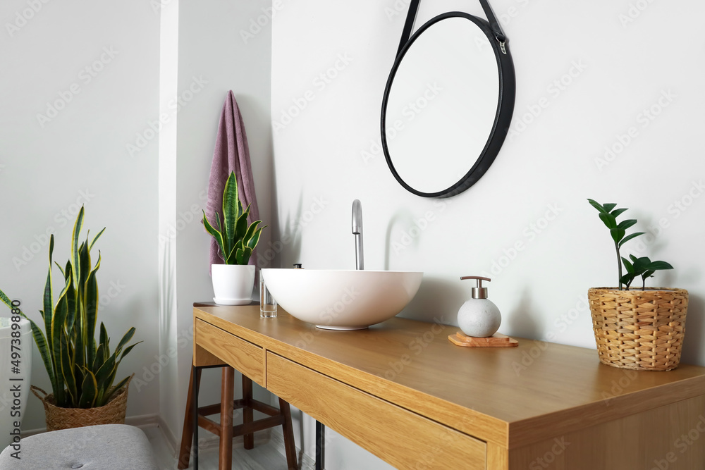 Table with sink and soap near light wall in bathroom