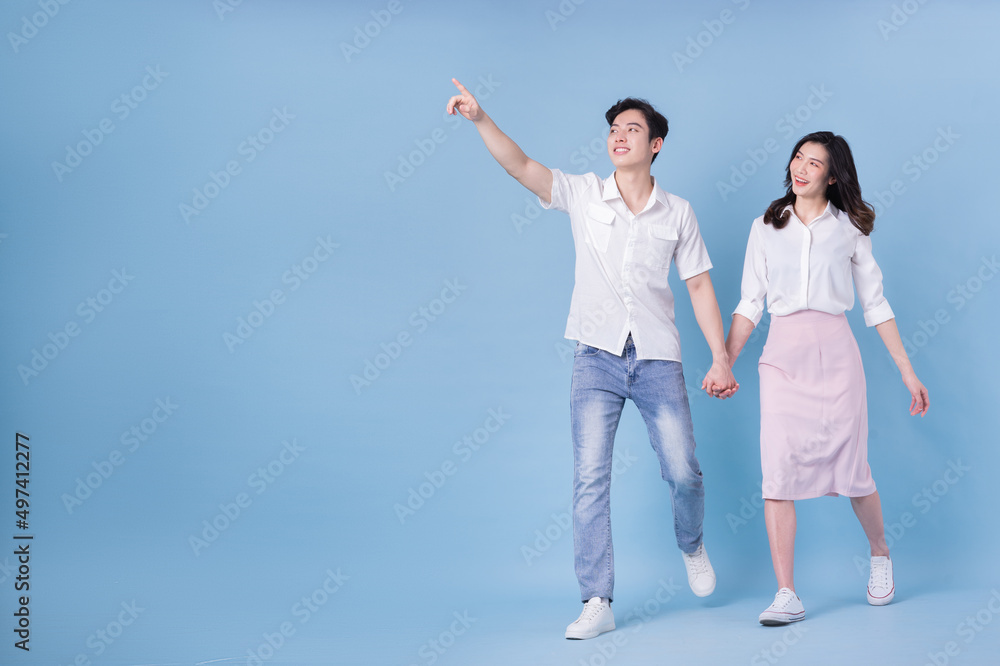 Full length image of young Asian couple on blue background