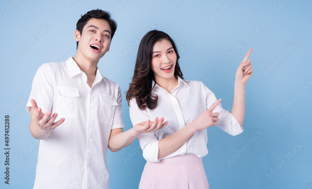 Image of young Asian couple posing on blue background