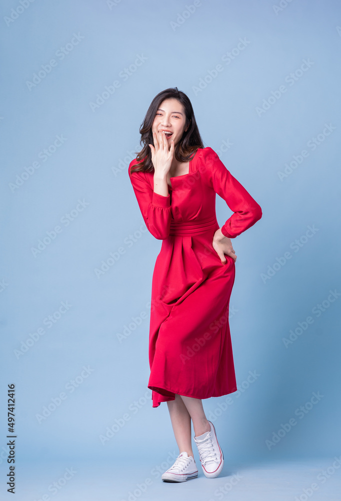 Full length image of young Asian woman wearing red dress on blue background