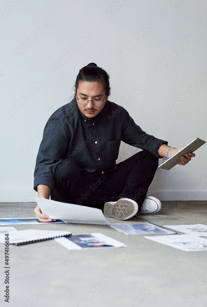 Hes got his hands full today. Full length shot of a handsome creative young businessman sitting on t