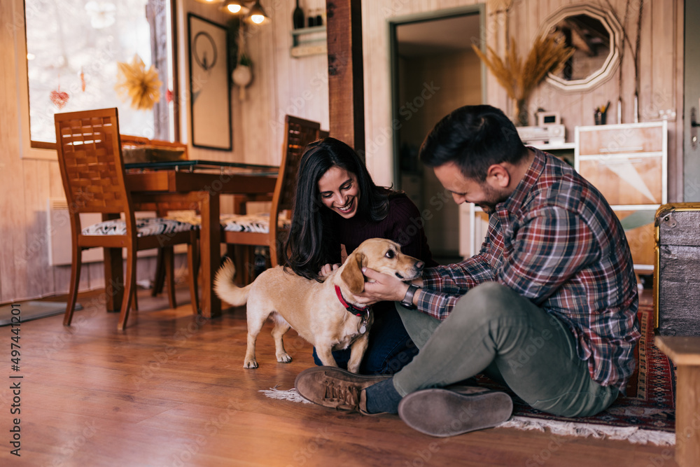 The happy adult couple, spending time with their lovely dog, giving a lot of attention.