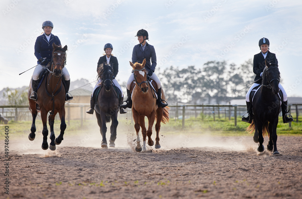 Theyre neck-and-neck. Full length shot of a group of attractive young female jockeys riding their ho