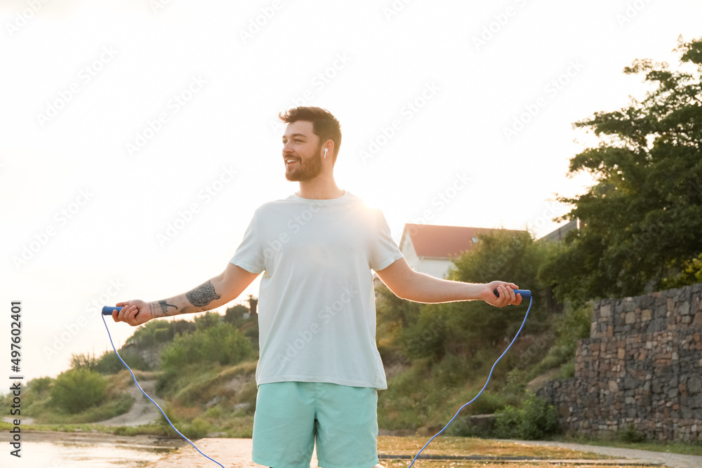 英俊男子晚上在河边跳绳