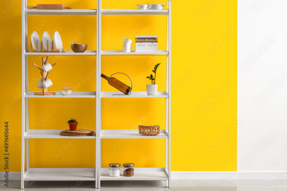 Modern shelving unit with dishware near color wall in kitchen