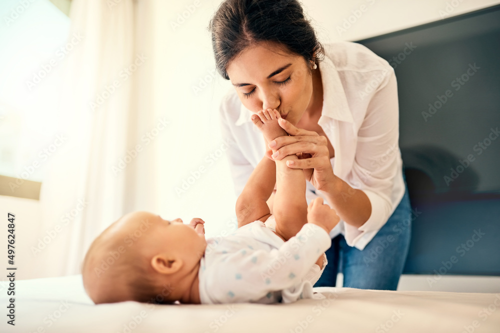 还有什么比婴儿脚趾更能亲吻的了。一位幸福的母亲在家里与她的男婴亲密相处的照片。